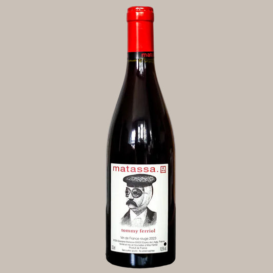 Red wine bottle with a label featuring a person's face and 'matassa' branding on a gray surface.
